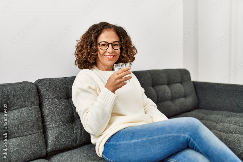 Middle age hispanic woman smiling confident drinking water at home Middle age hispanic woman smiling confident drinking water at home