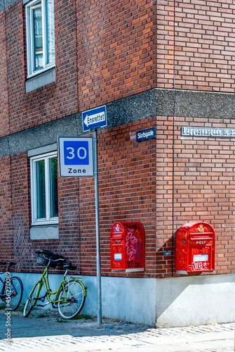 A street of Copenhaghen with bicyles, red post boxes and road signes. On the background a typical red brick building. photo