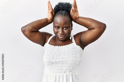 Young african woman standing over white isolated background doing bunny ears gesture with hands palms looking cynical and skeptical. easter rabbit concept.