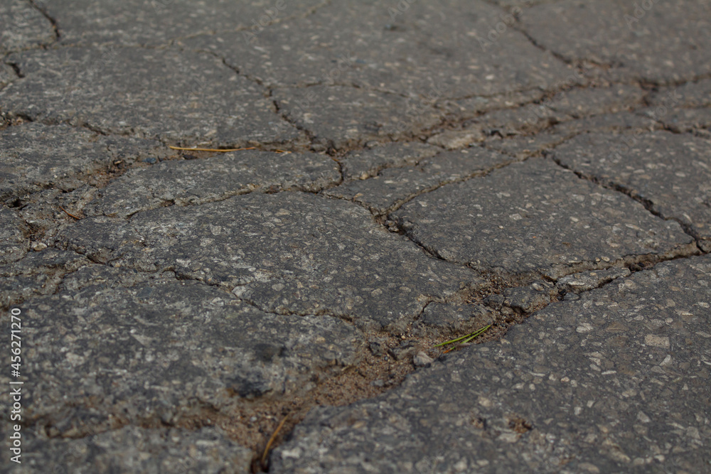 Obraz premium The texture of an asphalt road passing through the village. The road to the village. Dark-grey background texture of asphalt. Cracks in the asphalt. Destruction of the road