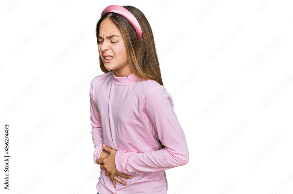 Beautiful brunette little girl wearing casual turtleneck sweater with hand on stomach because nausea, painful disease feeling unwell. ache concept. Beautiful brunette little girl wearing casual turtleneck sweater with hand on stomach because nausea, painful disease feeling unwell. ache concept.