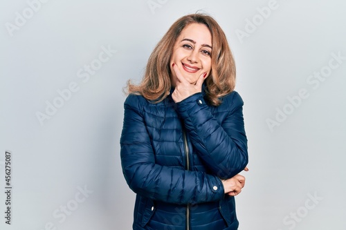 Middle age caucasian woman wearing casual clothes looking confident at the camera smiling with crossed arms and hand raised on chin. thinking positive.