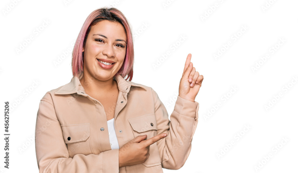 Hispanic woman with pink hair wearing casual clothes smiling and looking at the camera pointing with two hands and fingers to the side. Hispanic woman with pink hair wearing casual clothes smiling and looking at the camera pointing with two hands and fingers to the side.