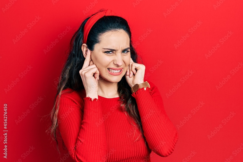 Young hispanic woman wearing casual clothes covering ears with fingers with annoyed expression for the noise of loud music. deaf concept. Young hispanic woman wearing casual clothes covering ears with fingers with annoyed expression for the noise of loud music. deaf concept.
