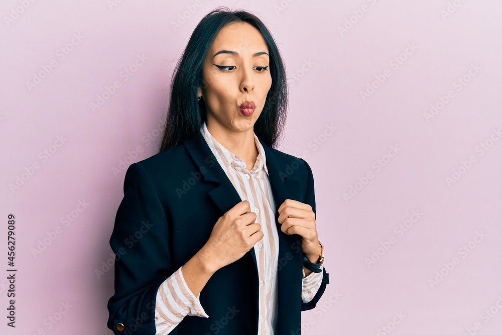 Young hispanic girl wearing business clothes making fish face with mouth and squinting eyes, crazy and comical.