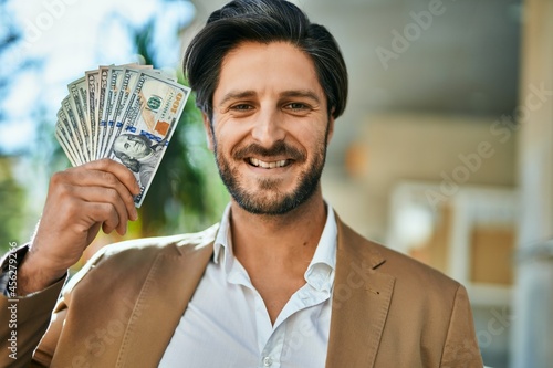 Young hispanic businessman smiling happy standing at the city.