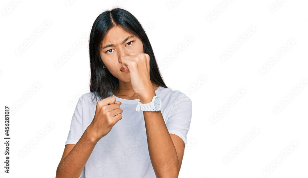 Beautiful young asian woman wearing casual white t shirt ready to fight with fist defense gesture, angry and upset face, afraid of problem Beautiful young asian woman wearing casual white t shirt ready to fight with fist defense gesture, angry and upset face, afraid of problem