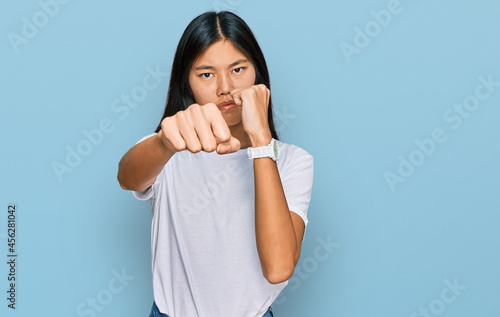 Obraz na plátně Beautiful young asian woman wearing casual white t shirt punching fist to fight,