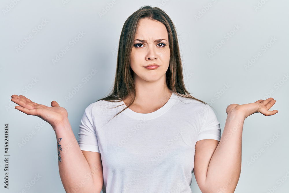 Young hispanic girl wearing casual white t shirt clueless and confused with open arms, no idea and doubtful face. Young hispanic girl wearing casual white t shirt clueless and confused with open arms, no idea and doubtful face.
