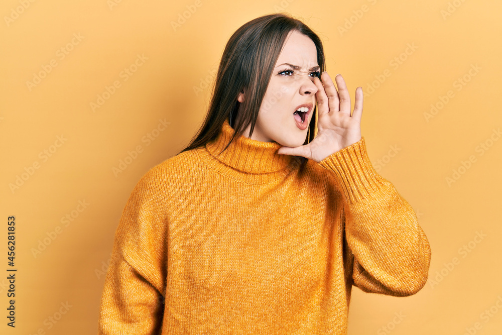 Young hispanic girl wearing casual clothes shouting and screaming loud to side with hand on mouth. communication concept. Young hispanic girl wearing casual clothes shouting and screaming loud to side with hand on mouth. communication concept.