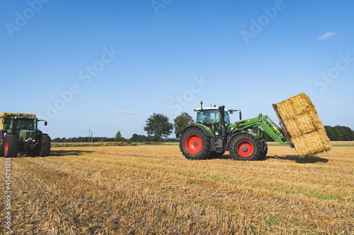 Strohernte - Traktor mit Frontlader beim Beladen eines Transportanh  ngers mit Strohballen.