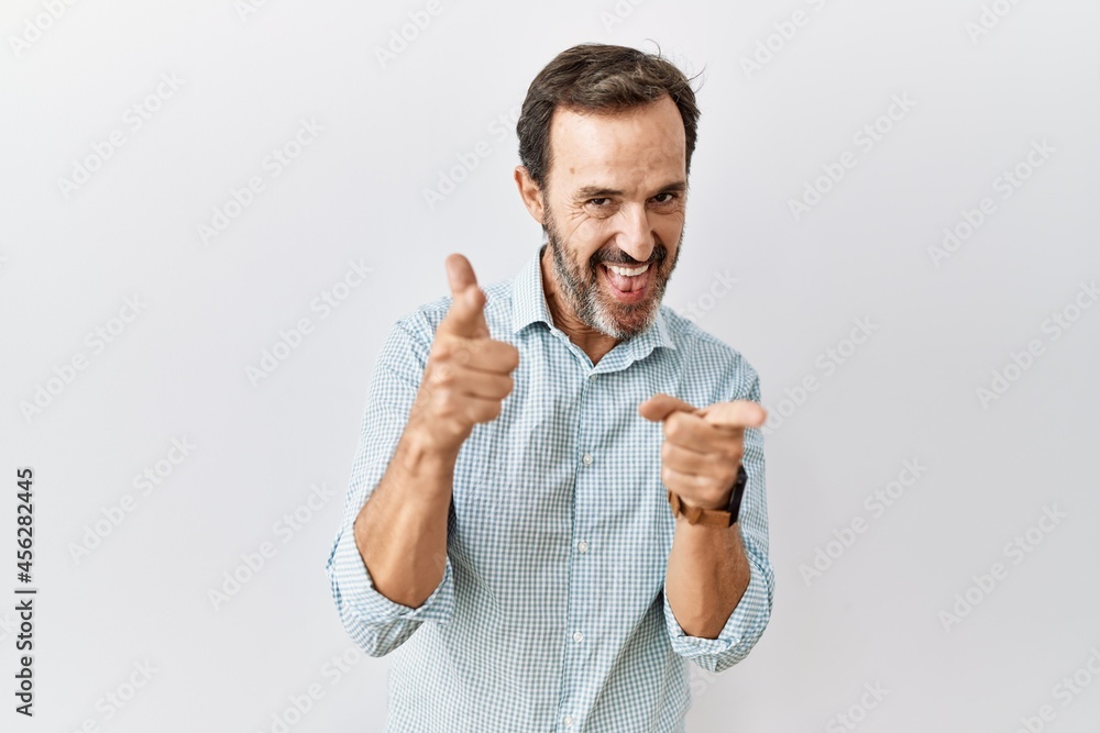 Middle age hispanic man with beard standing over isolated background pointing fingers to camera with happy and funny face. good energy and vibes. Middle age hispanic man with beard standing over isolated background pointing fingers to camera with happy and funny face. good energy and vibes.