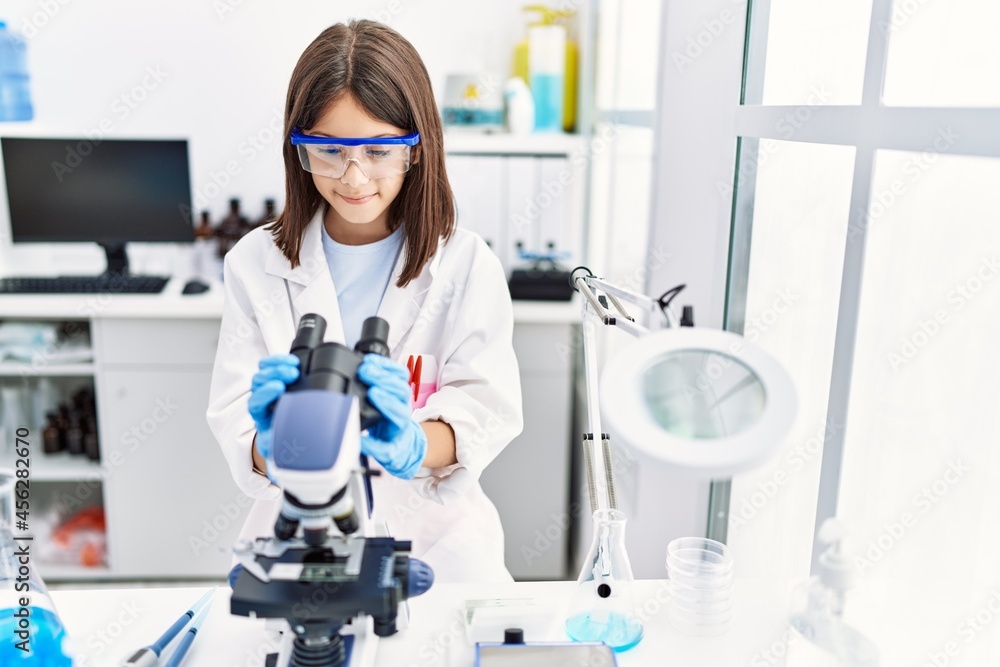 Young hispanic girl looking through microscope at laboratory Young hispanic girl looking through microscope at laboratory