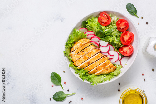 Bowl with salad and sliced chicken fillet. Diet lunch, keto diet, healthy food. Top view on white background.