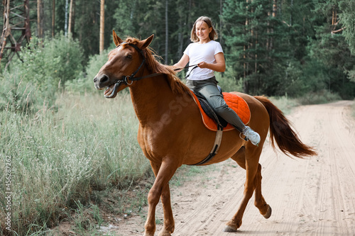 A girl rides a horse in the hot summer in the forest © Enigma