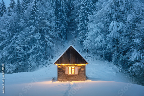 Canvas Print Fantastic winter landscape with glowing wooden cabin in snowy forest