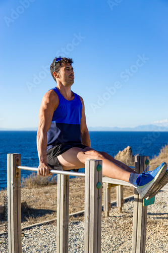 Caucasian young man doing sports on parallel bars in an outdoor park