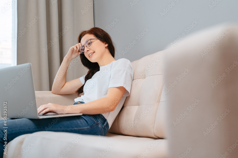 Young woman is looking for useful information on the Internet through a laptop while sitting at home. Young woman is looking for useful information on the Internet through a laptop while sitting at home.