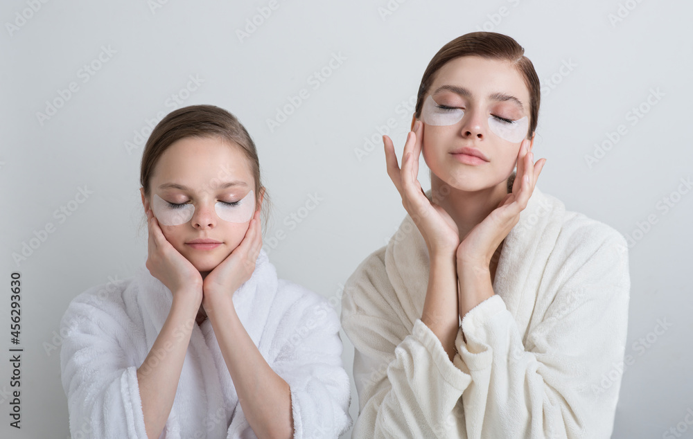 Two girls playing with cosmetic SPA mask and eye panda patches mask on their faces. Little girl and young woman enjoy home spa treatments. SPA and wellness concept Two girls playing with cosmetic SPA mask and eye panda patches mask on their faces. Little girl and young woman enjoy home spa treatments. SPA and wellness concept
