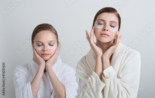 Two girls playing with cosmetic SPA mask and eye panda patches mask on their faces. Little girl and young woman enjoy home spa treatments. SPA and wellness concept