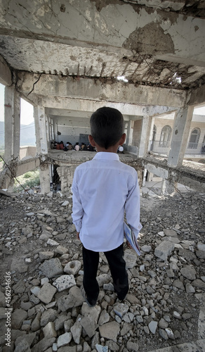  A Yemeni child looks at his classmates as they study at a school destroyed by war in Taiz, Yemen. photo