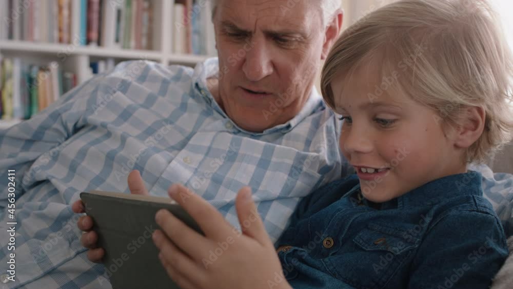 grandfather showing little boy how to use tablet computer teaching curious grandson modern technology intelligent child learning mobile device sitting with grandpa on sofa 4k grandfather showing little boy how to use tablet computer teaching curious grandson modern technology intelligent child learning mobile device sitting with grandpa on sofa 4k
