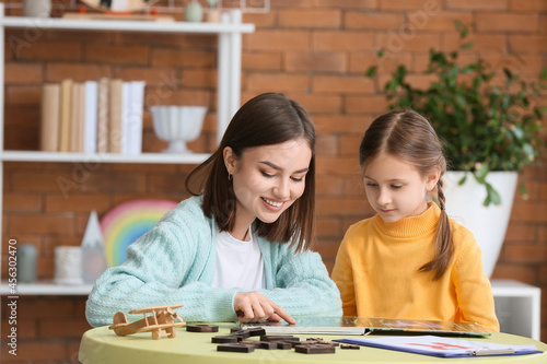 Speech therapist working with cute girl in clinic photo