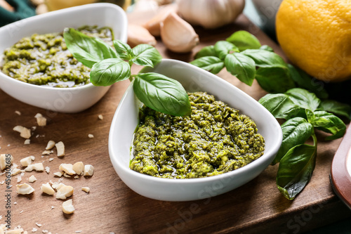Bowls with tasty pesto sauce and cheese on table, closeup