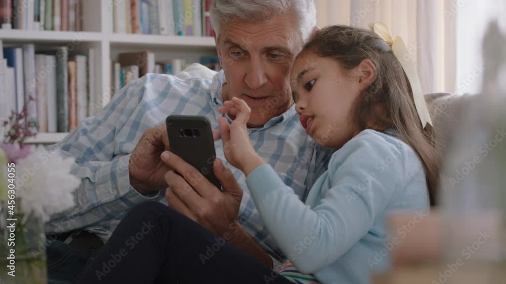 grandfather showing cute little girl how to use smartphone teaching curious granddaughter modern technology intelligent child learning mobile phone sitting with grandpa on sofa grandfather showing cute little girl how to use smartphone teaching curious granddaughter modern technology intelligent child learning mobile phone sitting with grandpa on sofa