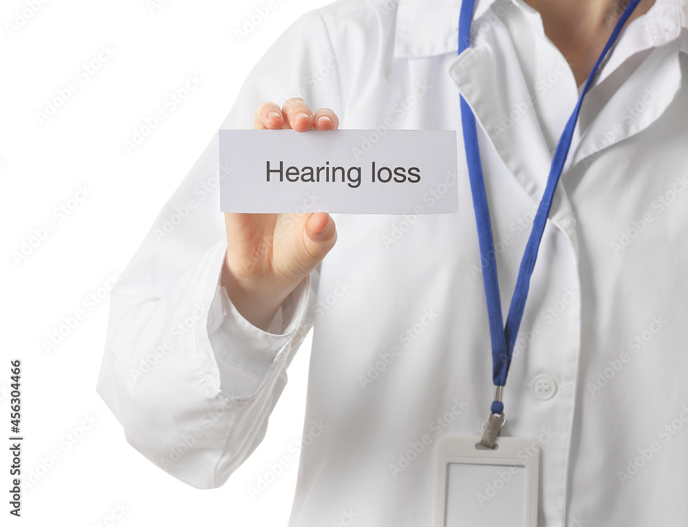 Female doctor holding paper with text HEARING LOSS on white background Female doctor holding paper with text HEARING LOSS on white background