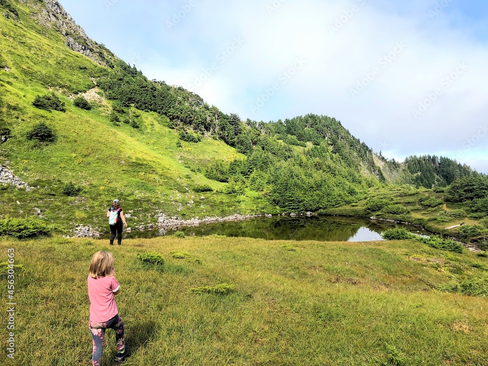 A mother and daughter in haida gwaii, british columbia, canada, doing the sleeping beauty hike. Hiking through a valley with a beautiful lake