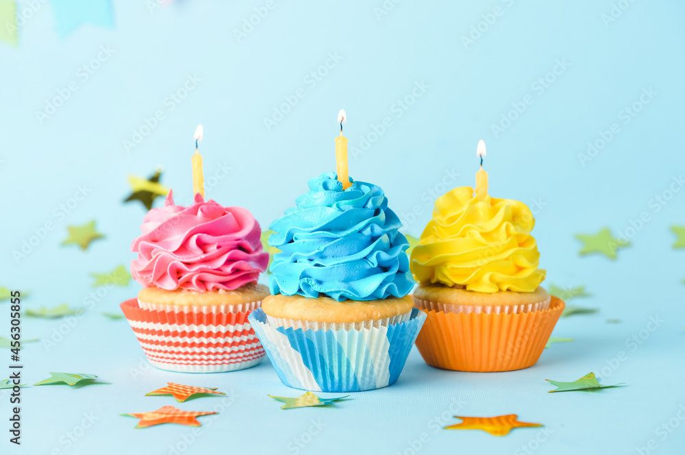 Tasty Birthday cupcakes with burning candles on color background Tasty Birthday cupcakes with burning candles on color background