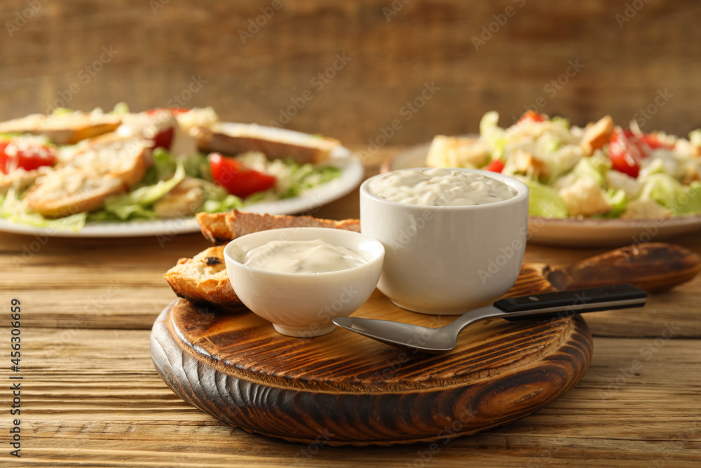 Bowls of tasty Caesar sauce and croutons on wooden background Bowls of tasty Caesar sauce and croutons on wooden background