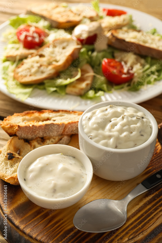 Bowls of tasty Caesar sauce and croutons on table Bowls of tasty Caesar sauce and croutons on table