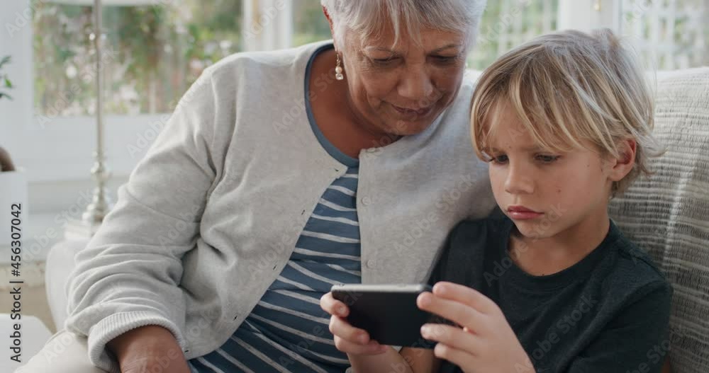happy little boy using smartphone showing grandmother how to use mobile phone teaching granny modern technology intelligent child helping grandma at home 4k happy little boy using smartphone showing grandmother how to use mobile phone teaching granny modern technology intelligent child helping grandma at home 4k