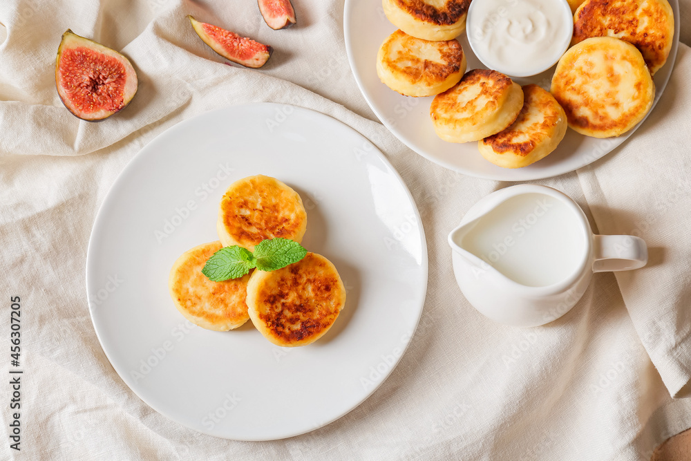 Plates with cottage cheese pancakes and milk on table
