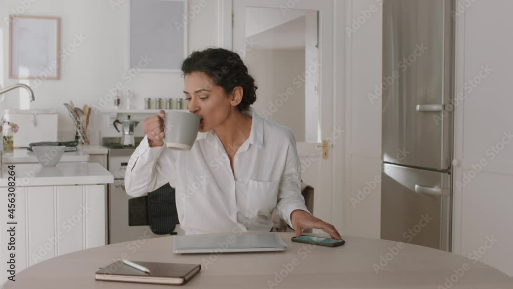 beautiful woman using laptop computer in kitchen checking email messages drinking coffee leaving for work 4k footage beautiful woman using laptop computer in kitchen checking email messages drinking coffee leaving for work 4k footage