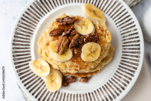 Protein pancakes topped with banana, syrup and glazed pecans. Healthy diet flapjacks. 