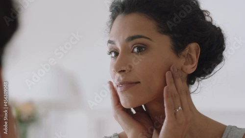 portrait beautiful young woman looking in mirror at perfect healthy skin touching face with hands enjoying smooth natural complexion with anti aging skincare getting ready at home beauty concept