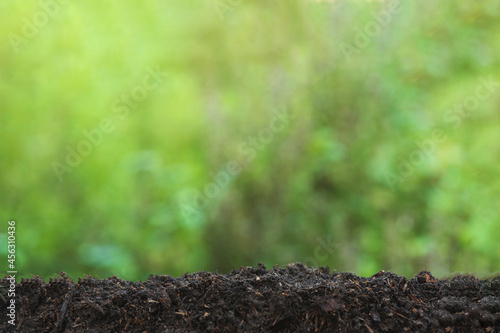 Background concept. Pile of soil on a green bokeh background with copy space.