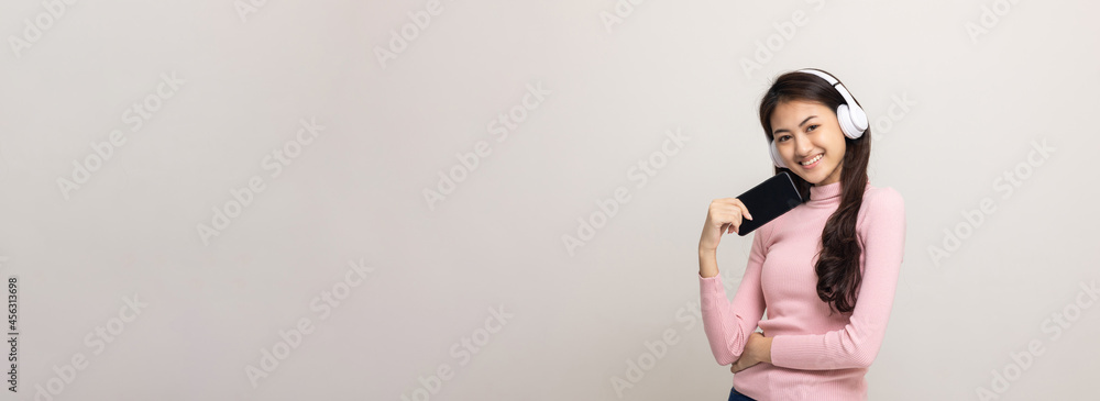 © Chanakon - Beautiful young asian women choose song and play music from smartphone connection with wireless headphone having fun in home. Teenage girl listen to the music enjoy relaxing on isolated background.
