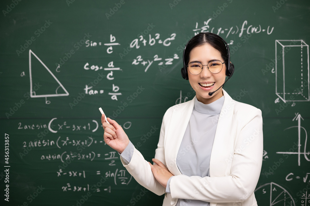 Young asian teacher woman holding chalk teaching video conference with student. Female teacher training the mathematics in classroom blackboard online course.