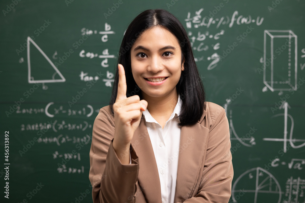 Young asian teacher woman standing looking at camera and video conference with student. Female teacher training the mathematics in classroom blackboard from online course. Young asian teacher woman standing looking at camera and video conference with student. Female teacher training the mathematics in classroom blackboard from online course.