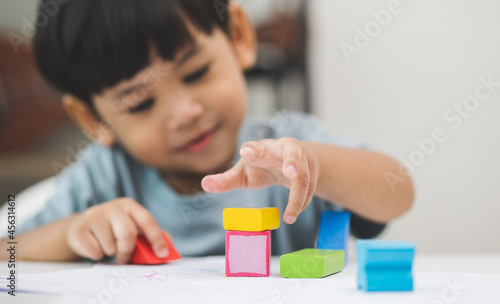 Close up Children hand Practice the skills of playing with wooden toys on the table in living room. Asian little boy education from home. Developing children's learning before entering kindergarten
