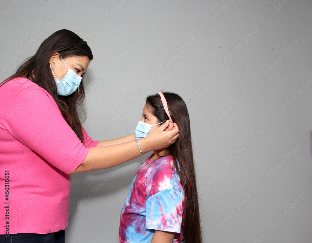 Hispanic Latina Mom and Daughter Putting on Face Masks in Quarantine Due to Covid-19 Pandemic
