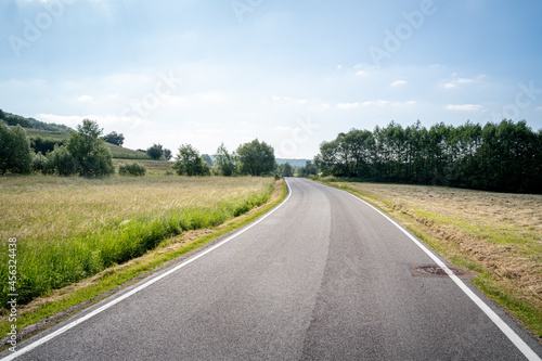 Nice road in the landscape with grass, trees and blue sky 