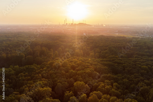Drone view over forest and trees and an industrial area during the sunset in the ruhr area in Germany