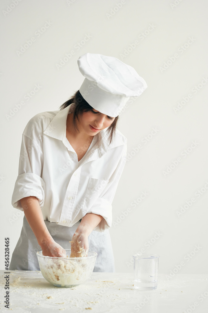 woman baker in cook uniform works with dough flour products woman baker in cook uniform works with dough flour products