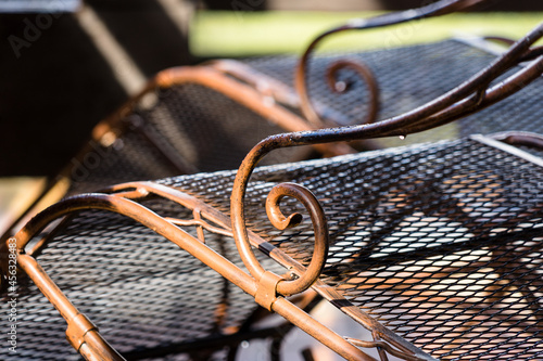 Close-up of vintage metal deck chairs in a row with sun spots and shadows photo