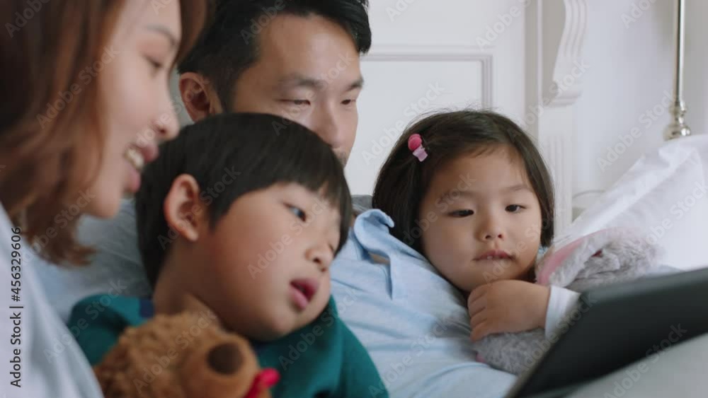 happy asian family using tablet computer at home mother and father with children watching entertainment playing game on touchscreen device learning having fun relaxing in bed 4k footage happy asian family using tablet computer at home mother and father with children watching entertainment playing game on touchscreen device learning having fun relaxing in bed 4k footage